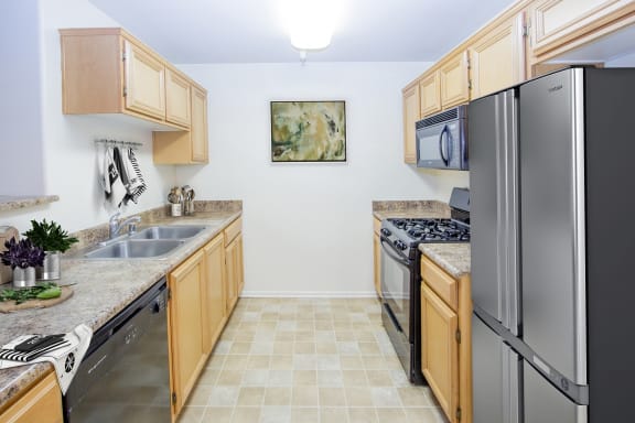 a kitchen with wooden cabinets and stainless steel appliances at Dronfield Astoria Apartments ,Sylmar, California,  CA