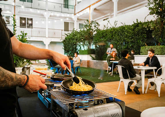 A person is cooking noodles on a stove.