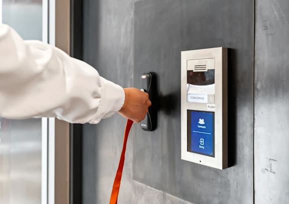 A person is pulling a red cord from a wall-mounted device.