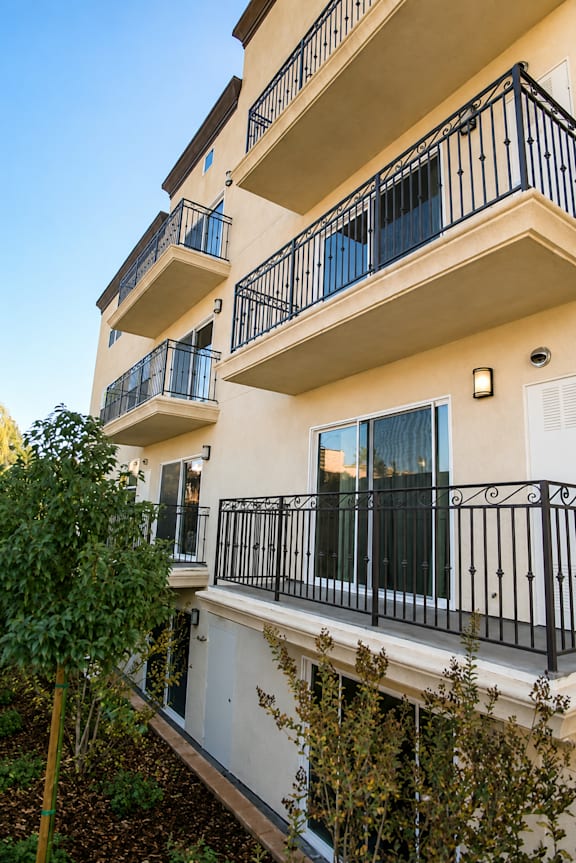 A building with balconies and a tree in front.