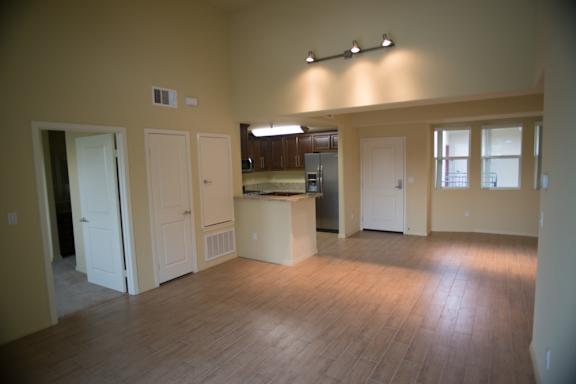A kitchen area with a counter and cabinets is visible through the open door.