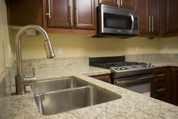 A kitchen with a stainless steel sink and a silver faucet.