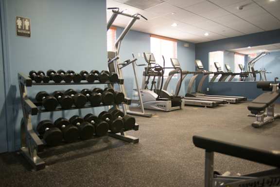 A gym with a variety of equipment including dumbbells, weight machines, and benches.