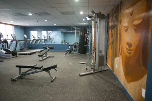 A gym with a variety of equipment including treadmills, weights, and exercise machines.