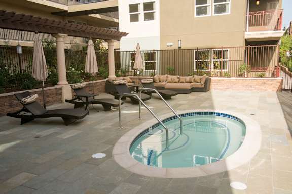 A small pool with a hot tub in the middle of a patio.
