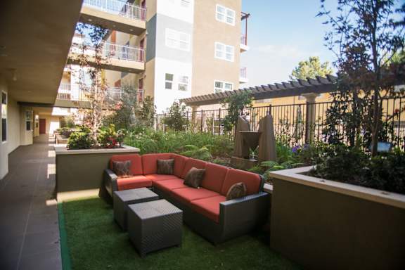 A patio with a red couch and grey table.