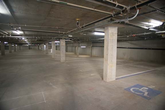 A parking garage with a blue and white handicap sign on the concrete floor.