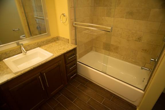 A bathroom with a sink, mirror, and tiled shower.