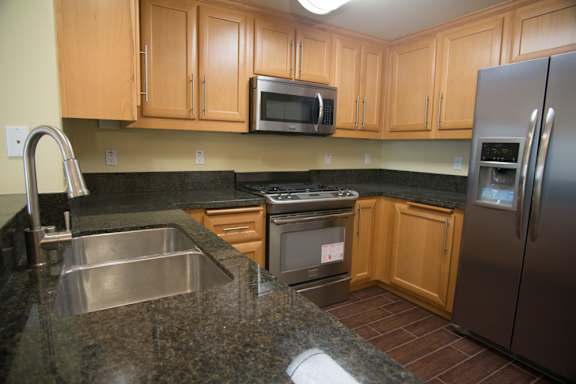 A kitchen with a stainless steel refrigerator and a microwave above the stove.