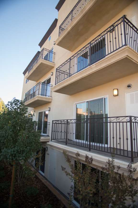 A building with balconies and a tree in front.
