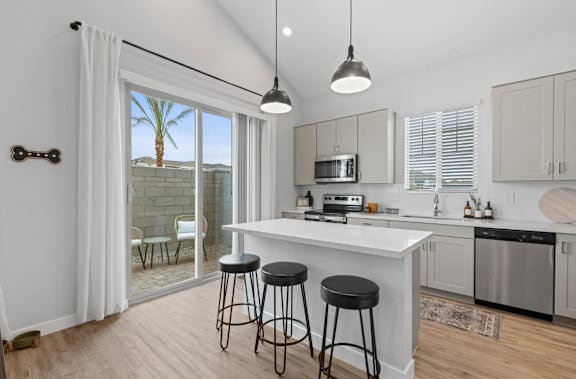 A kitchen with a white counter and black stools. at Village of Chandler Apartments, Arizona, 85249