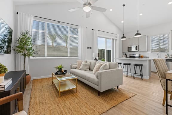 A living room with a grey couch and a wooden coffee table. at Village of Chandler Apartments, Chandler, AZ