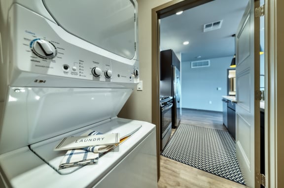 a laundry room with a washer and dryer and a hallway to a kitchen at Cuvee, Glendale, 85305