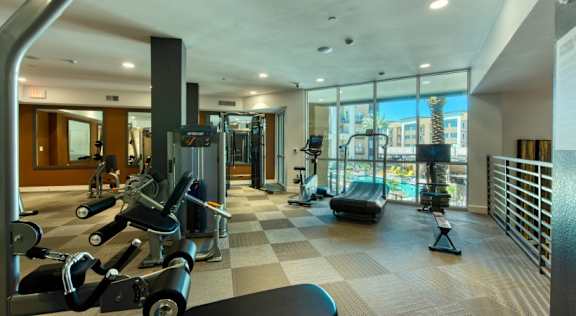Upgraded gym with cardio equipment and a large window with a view of the city at Elevation SanTan