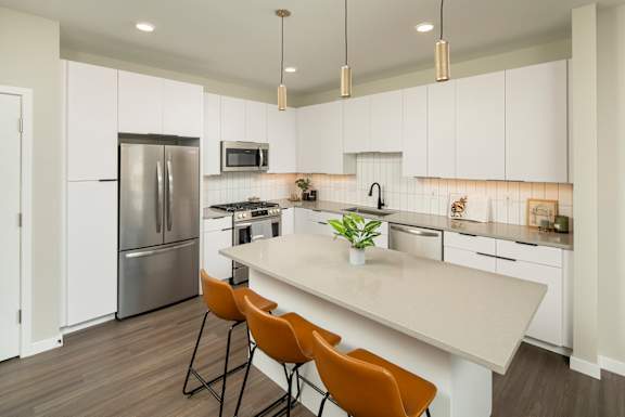 A kitchen with a refrigerator, microwave, and a counter with chairs.at Huxley Scottsdale, Scottsdale, AZ