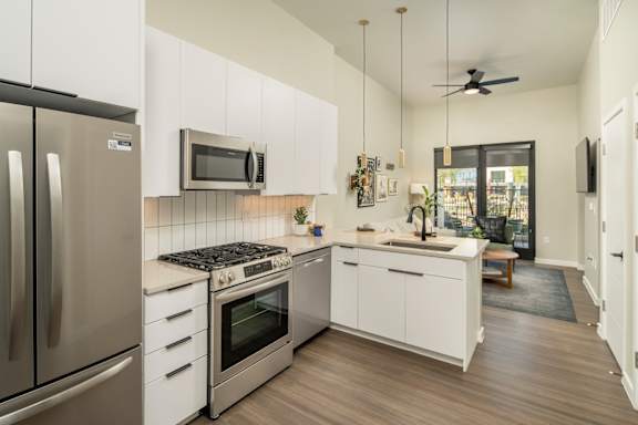 A modern kitchen with gas stove, stainless steel appliances, quartz counters and white cabinetry.at Huxley Scottsdale, Arizona, 85260