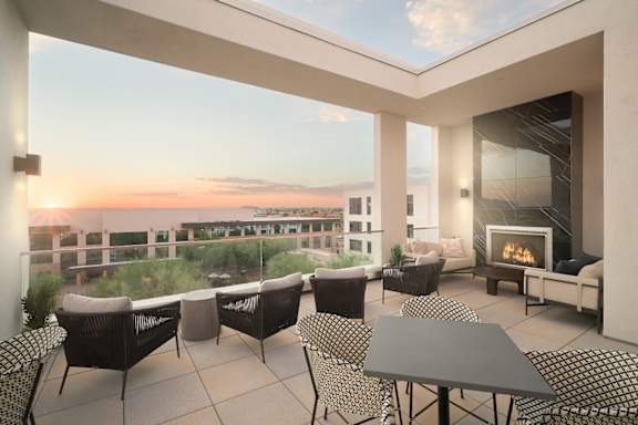 A roof top patio with a fireplace and chairs overlooking a cityscape at sunset.at Huxley Scottsdale, Scottsdale Arizona