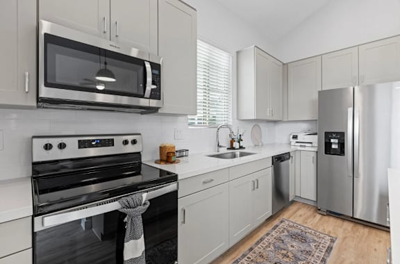 A modern kitchen with a stove, microwave, and refrigerator at Village of Chandler Apartments, Arizona