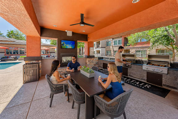 A group of people are sitting at a table under a covered patio area.