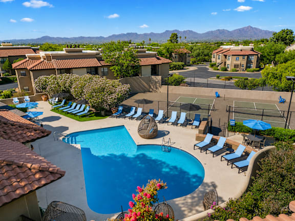 A pool surrounded by lounge chairs and umbrellas.