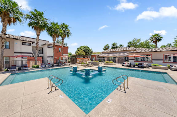 A swimming pool surrounded by palm trees and buildings.