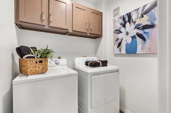 A laundry room with a basket of clothes and a washer and dryer.