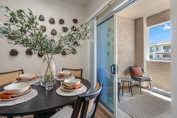 A dining table with chairs and a vase with a plant in it.
