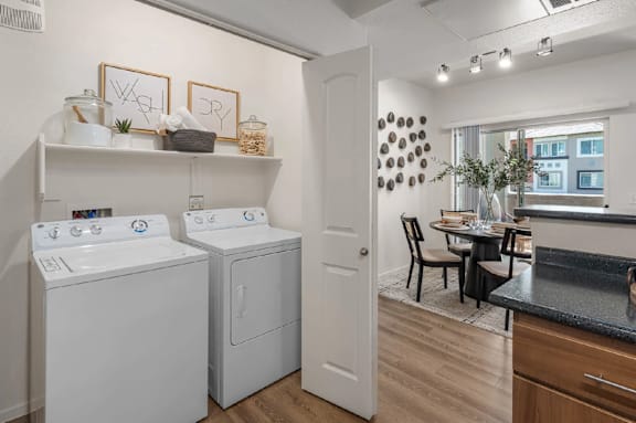 A laundry room with a washer and dryer, a table with chairs, and a window.