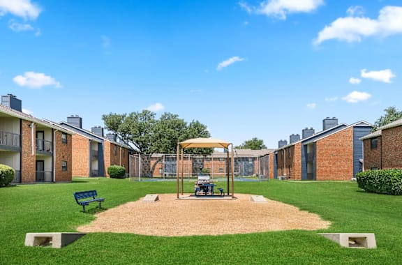 A playground area with a swing set and benches is surrounded by apartment buildings.