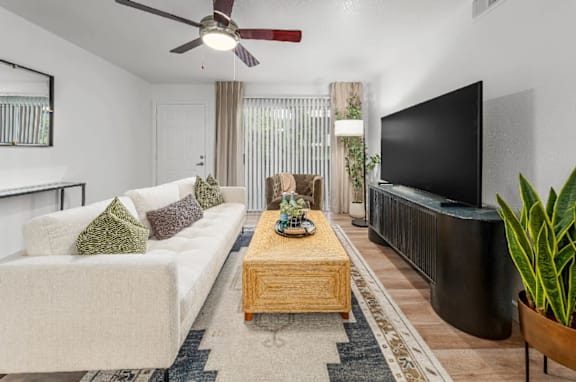 A living room with a white couch, a wooden coffee table, and a flat screen TV.