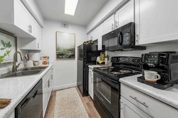 A modern kitchen with black appliances and white cabinets.
