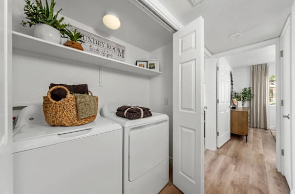 A laundry room with a washer and dryer and a basket on top of the washer.