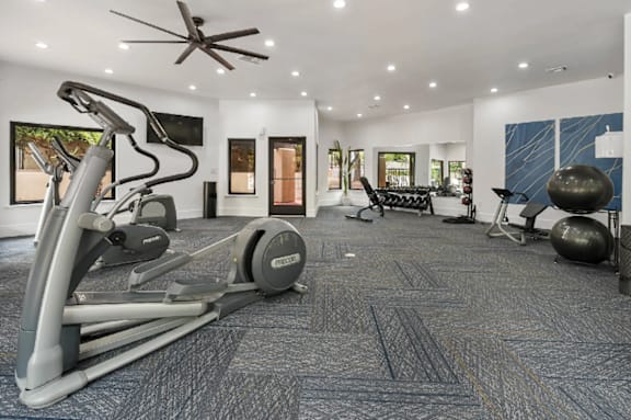 A home gym with a treadmill, elliptical trainer, and weights.