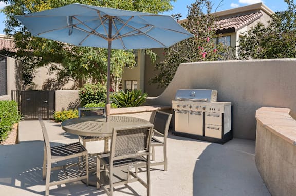 A patio with a table and chairs under an umbrella.