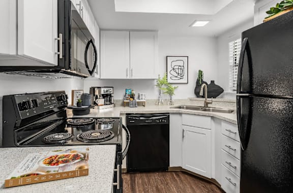 A modern kitchen with black appliances and white cabinets.