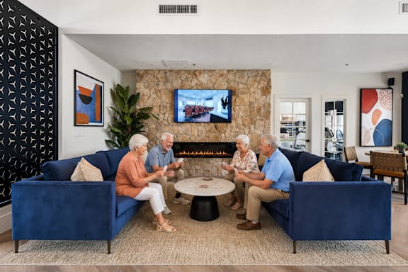 Three elderly people sitting on a couch in a living room.