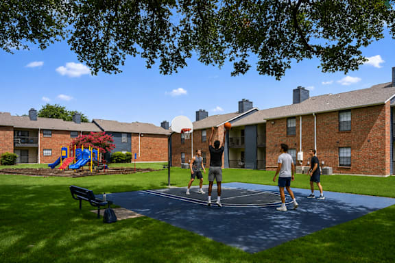 A group of people playing volleyball on a court in a park.