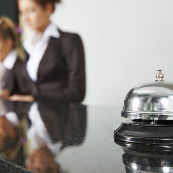 two women at the front desk of an apartment building and a concierge bell