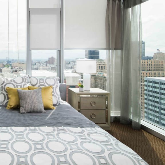 a bedroom with floor-to-ceiling windows and views of the city