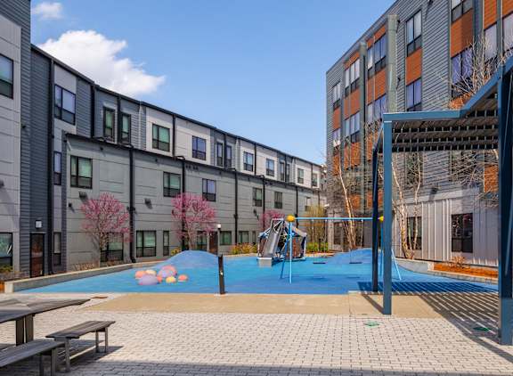 A playground area with a slide and swimming pool in front of apartment buildings.