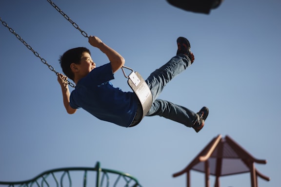 A boy is swinging on a swing set.
