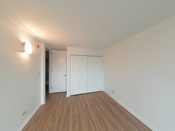A room with a white door and a white wall with a light switch.