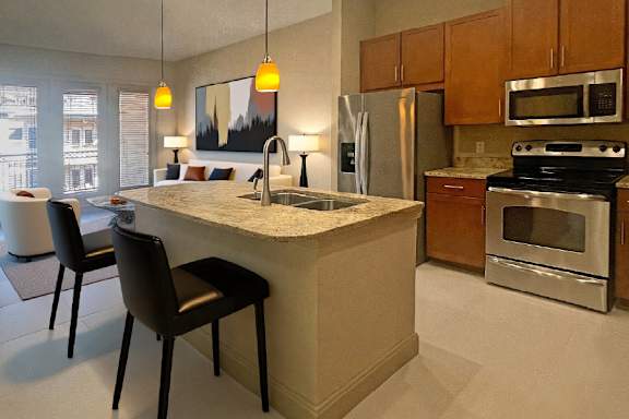 Luxury apartments next to the Galleria in Dallas with granite countertops, stainless steel appliances, built-in wine rack, kitchen island, and porcelain tile floor at Villa Piana Apartments in Dallas