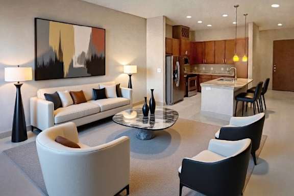 A modern living room with a large painting on the wall and a kitchen area in the background.