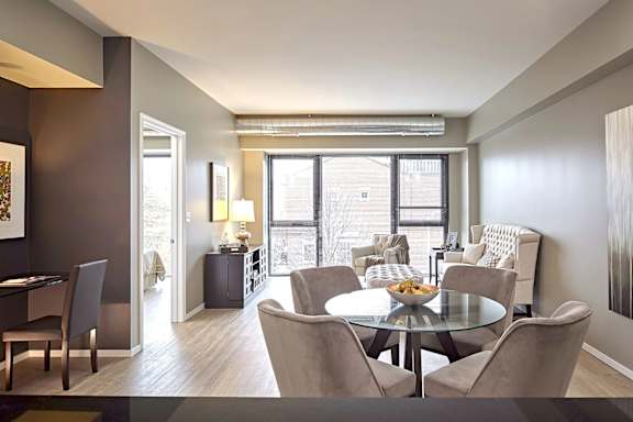 A dining room with a glass table surrounded by chairs.