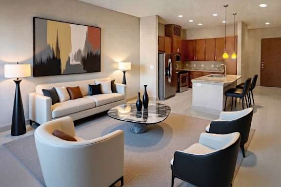A modern living room with a large painting on the wall and a kitchen area in the background.