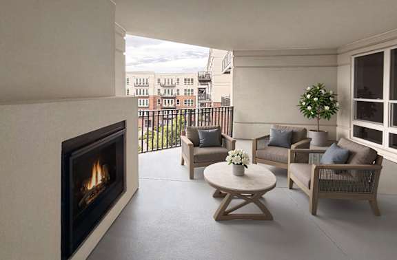 Spacious covered balcony with gas fireplace and scenic views of a beautifully landscaped courtyard at Xenia Apartments in Golden Valley Minnesota