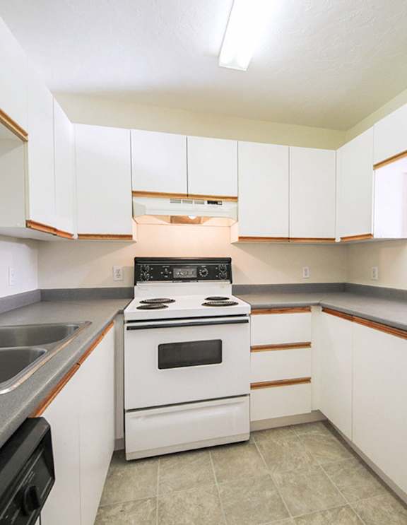 A modern kitchen with a stainless steel refrigerator and wooden flooring.