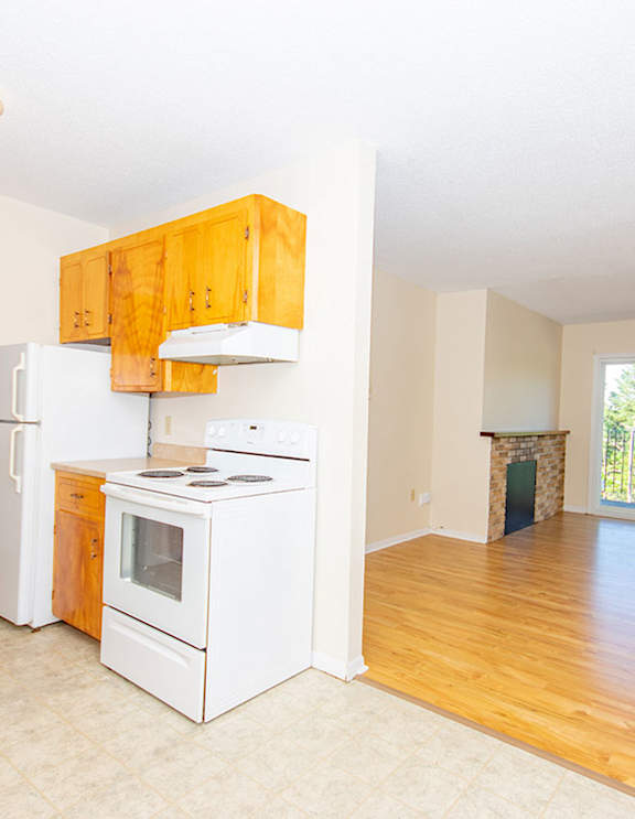 A modern kitchen with a stainless steel refrigerator and wooden flooring.