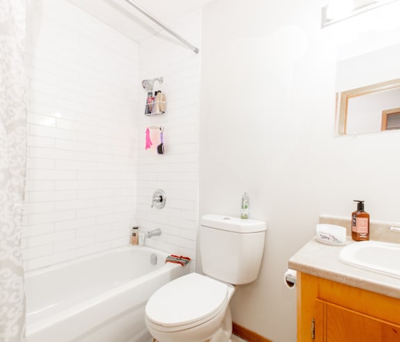 A white toilet sits next to a bathtub in a bathroom.
